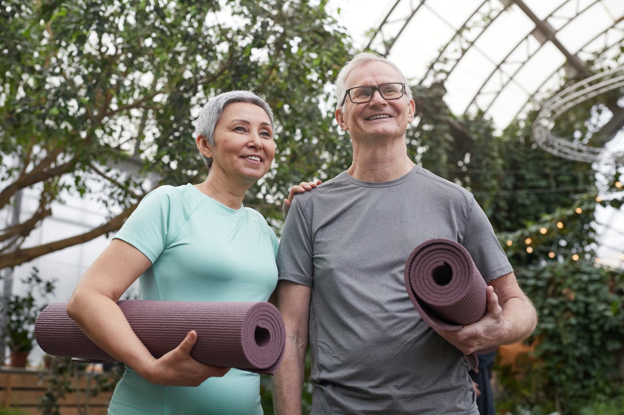Uomo maturo sorridente con tappetino da yoga, esempio di salute e vitalità naturale.