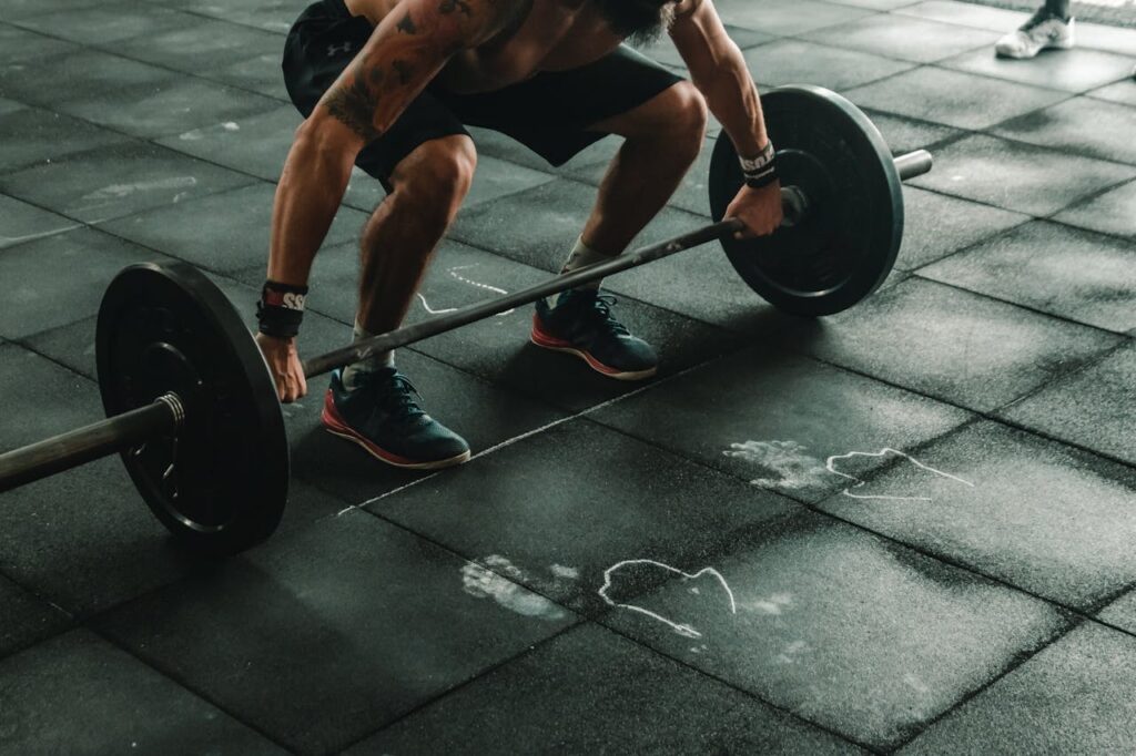 Uomo che solleva manubri in palestra, simbolo di forza muscolare e allenamento maschile.