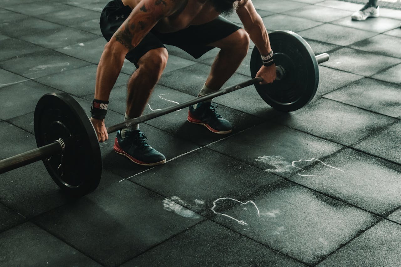 Uomo che solleva manubri in palestra, simbolo di forza muscolare e allenamento maschile.