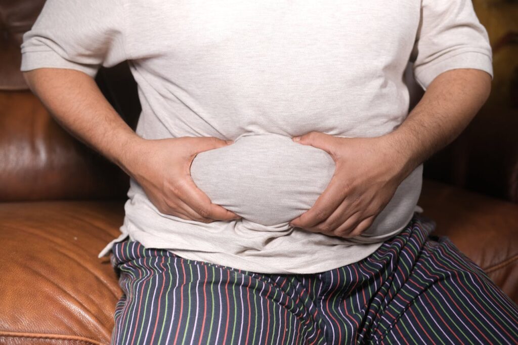 Uomo con pancia gonfia e sovrappeso, fattore di rischio per la fertilità maschile.