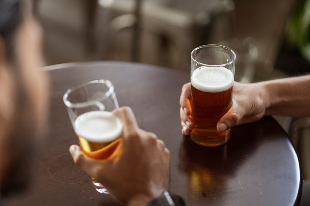 pexels-ketut-subiyanto-5054695 Due uomini che brindano con bicchieri di birra, rappresentazione del consumo sociale di alcol nella vita quotidiana maschile.
