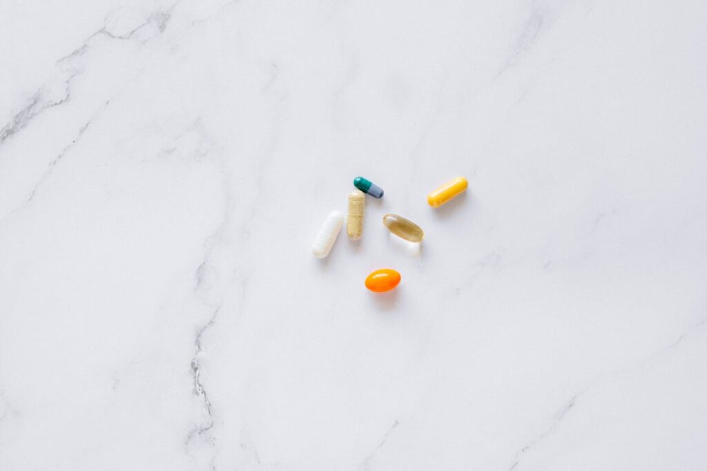 pexels-n-voitkevich-7615410 Diverse capsule e compresse colorate su sfondo bianco, rappresentazione visiva della scelta tra farmaci per la disfunzione erettile.