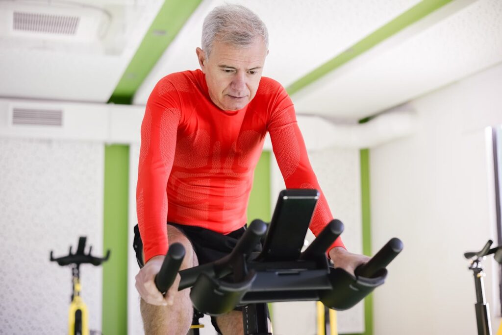 Uomo maturo impegnato in un allenamento aerobico su cyclette, per accelerare il metabolismo dopo i 40
