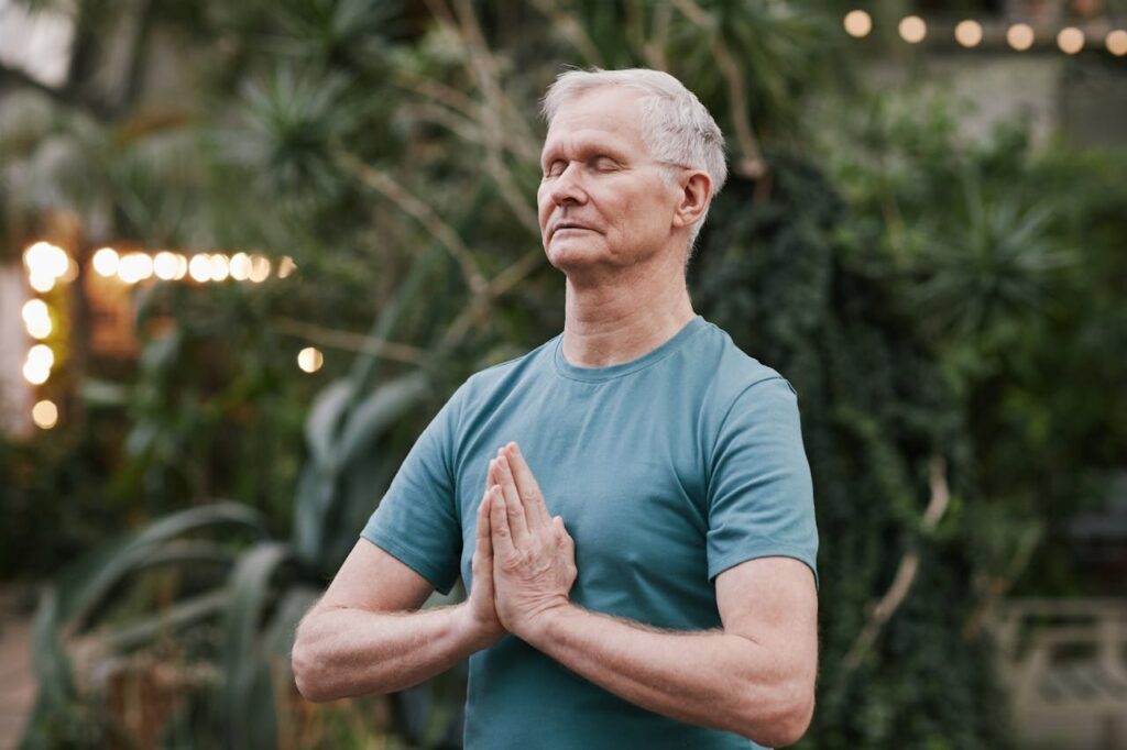 Uomo over 40 che pratica yoga all'aperto per ridurre lo stress e favorire l'attivazione del metabolismo