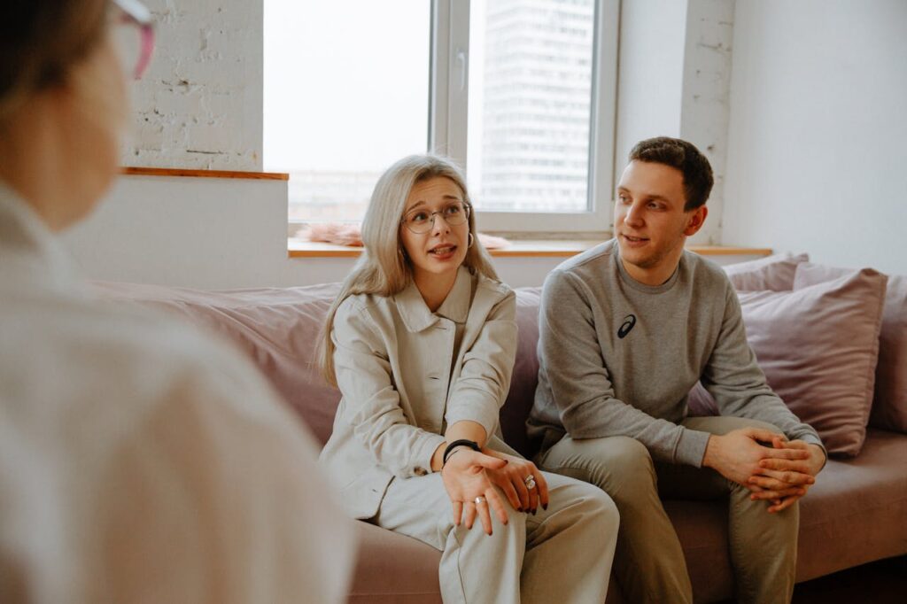 Una coppia matura seduta davanti a uno psicologo durante una seduta di terapia di coppia, entrambi i partner esprimono serenamente le proprie emozioni.