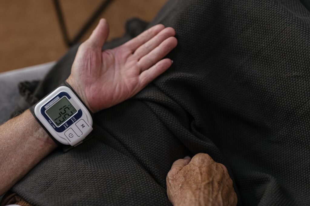 Uomo maturo misura la pressione arteriosa con un dispositivo digitale domestico.