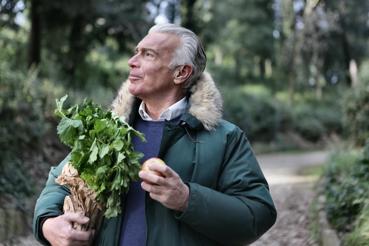 Uomo maturo che tiene in mano delle verdure fresche, simbolo di uno stile di vita sano per sostenere energia ed equilibrio ormonale.